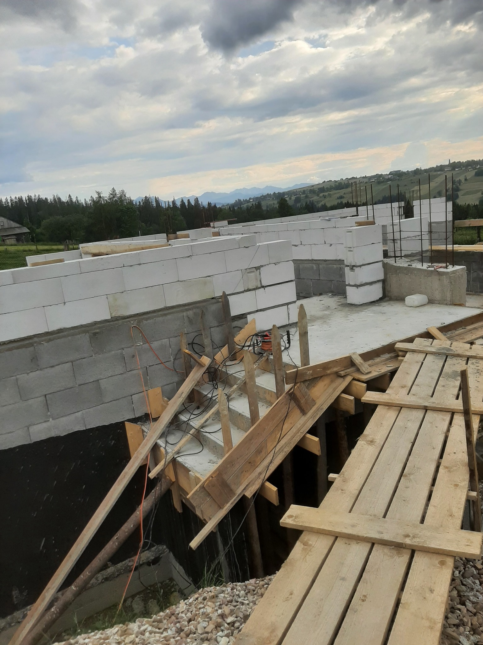 Budowa domu z betonu komórkowego w Maruszynie, widoczne fundamenty, ściany parteru oraz drewniane rusztowanie.