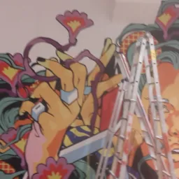 Kolorowy mural z motywami kwiatowymi i portretem kobiety, częściowo zasłonięty przez aluminiową drabinę rozstawną podczas prac wykończeniowych na ścianie.