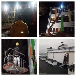 Cztery kadry z prac na wysokościach: pracownik w żółtej kurtce z logo na tle budynku, podnośnik koszowy oświetlający elewację, zbliżenie pracownika w podnośniku i robotnik na dachu budynku z kominami.