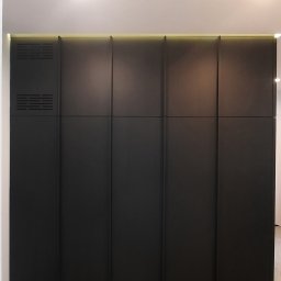 Rivej Sergii Yatsunov - Ciemna, nowoczesna szafa wnękowa z perforowanym panelem wentylacyjnym, oświetleniem LED i minimalistycznym designem.