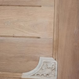 Rivej Sergii Yatsunov - Detal wykończenia drewnianej szafy z dekoracyjnym, rzeźbionym narożnikiem. Widoczna struktura drewna i precyzja wykonania.