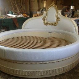 Rivej Sergii Yatsunov - Okrągłe, białe łóżko z drewnianym stelażem i zdobieniami w stylu retro, widoczne w warsztacie stolarskim podczas produkcji.