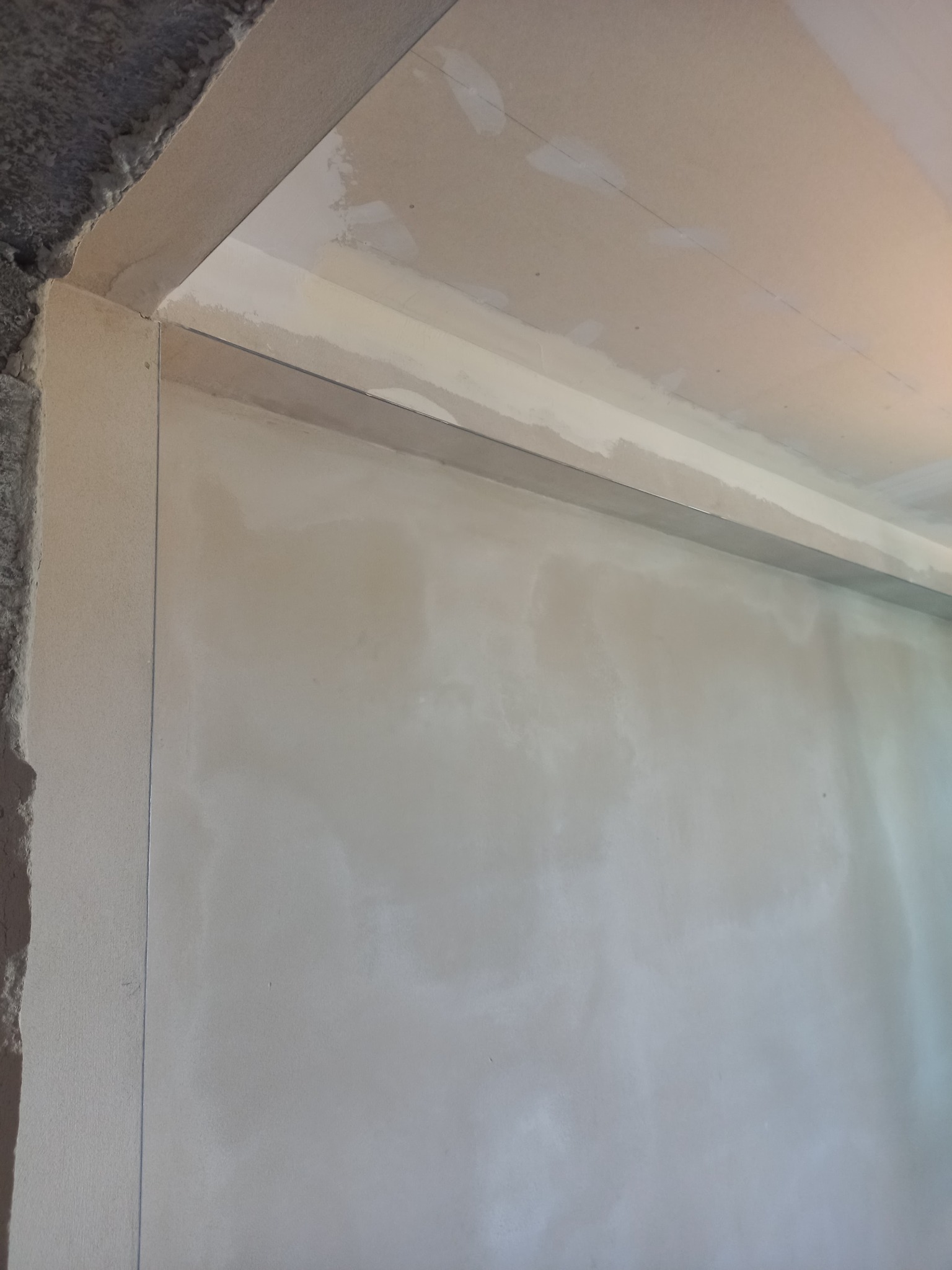 Ściana i sufit w trakcie przygotowania do malowania, widoczne ślady po szpachlowaniu i łączenia płyt kartonowo-gipsowych.