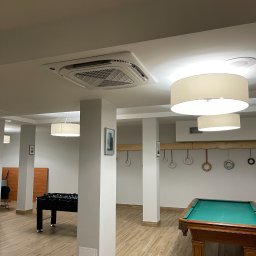 TRAVEL INVEST GROUP SPÓŁKA Z OGRANICZONĄ ODPOWIEDZIALNOŚCIĄ - Kasetonowa jednostka klimatyzacyjna Carrier zamontowana w suficie jasnego pomieszczenia rekreacyjnego z bilardem i piłkarzykami.