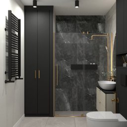 Emilia Cisek - Nowoczesna łazienka z czarnymi akcentami: kabina prysznicowa typu walk-in z marmurowymi płytkami, biała umywalka nablatowa, wisząca toaleta i wysoka szafka z grzejnikiem drabinkowym.
