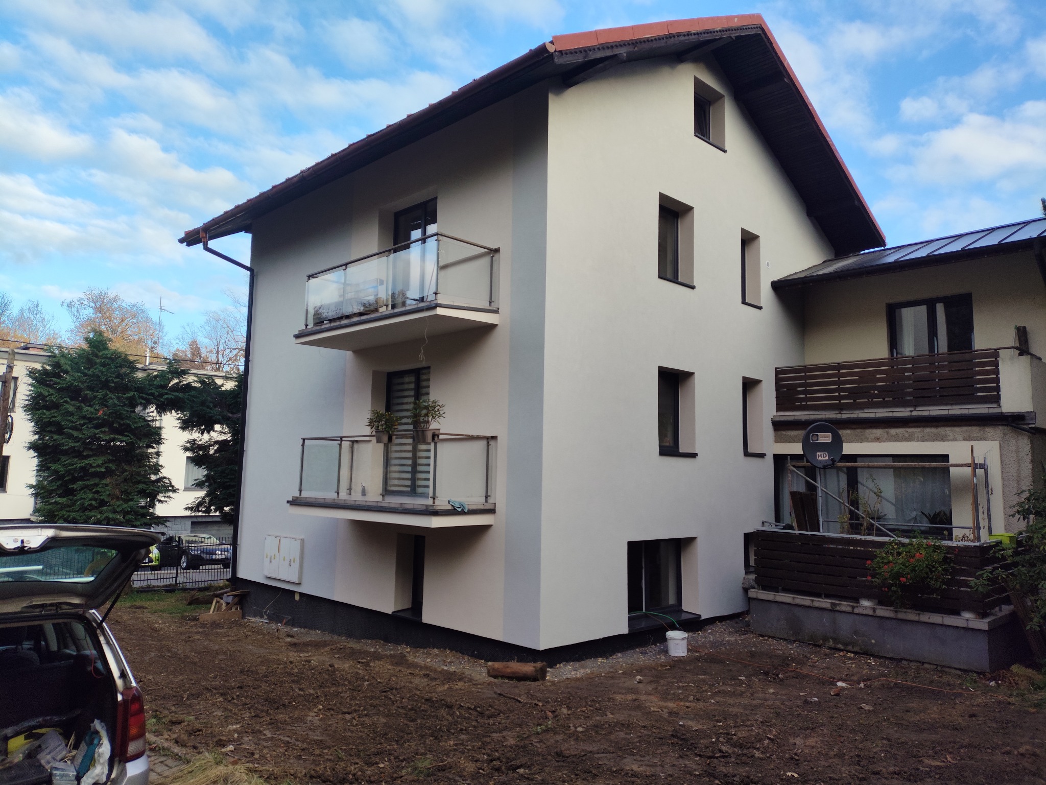 Odnowiona elewacja budynku wielorodzinnego z balkonami w Cieszynie. Jasna kolorystyka, nowoczesny wygląd. Widoczne detale wykończenia i otoczenie budynku.