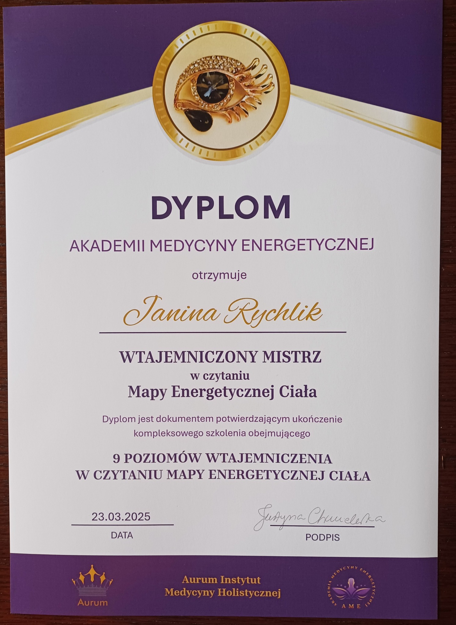 Dyplom Akademii Medycyny Energetycznej dla Janiny Rychlik, potwierdzający ukończenie szkolenia w czytaniu map energetycznej ciała, z datą 23.03.2025 i logotypami Aurum Instytut Medycyny...