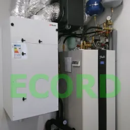 Zainstalowany system grzewczy z gruntową pompą ciepła Danfoss DHP-H Opti Pro+ 6 kW i rekuperatorem NILAN Comfort 302 Top, widoczne rury wentylacyjne i zbiorniki wyrównawcze w pomieszczeniu...