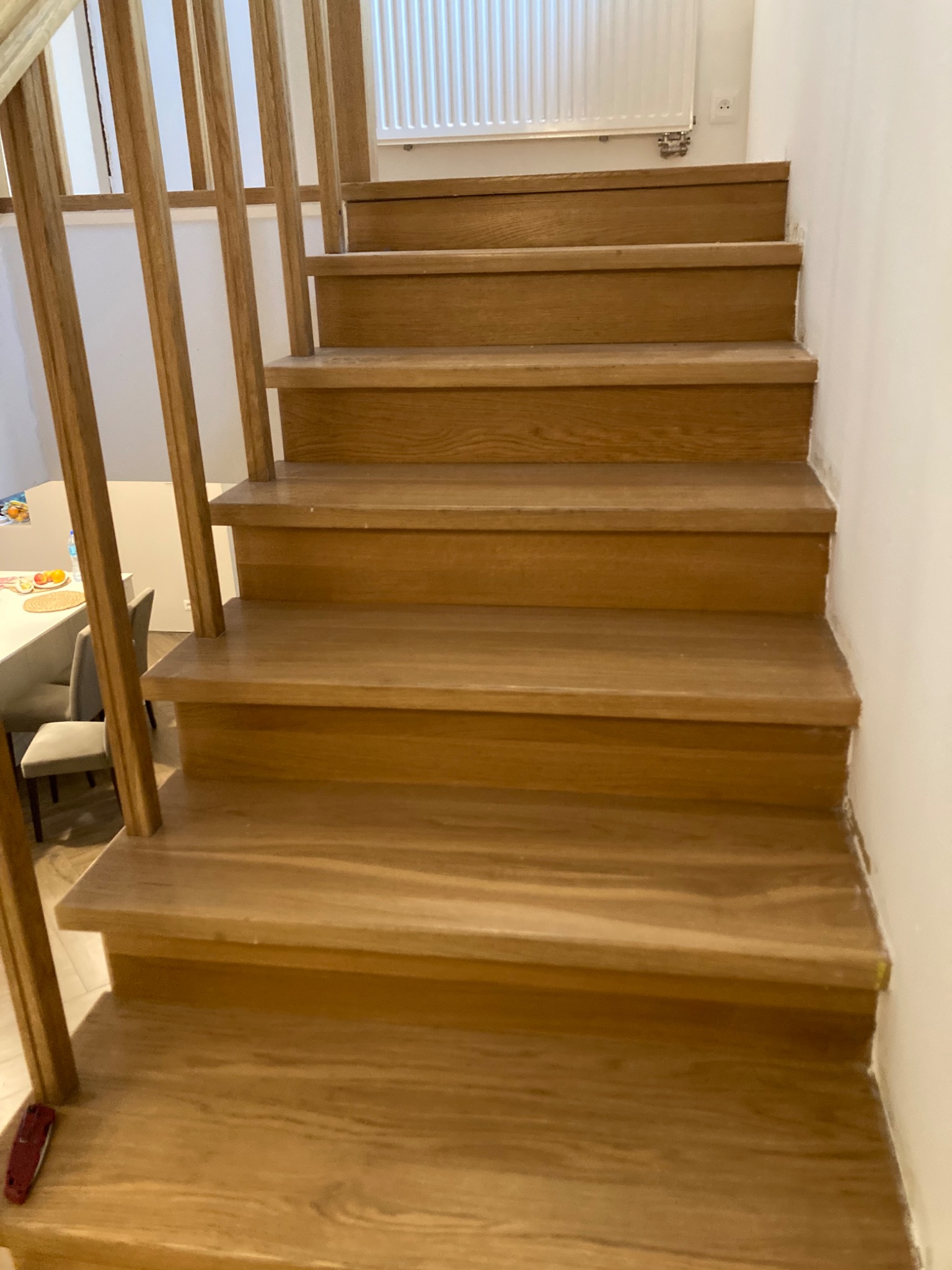 Jasne, drewniane schody z prostymi balustradami w jasnym wnętrzu, widok z dołu.