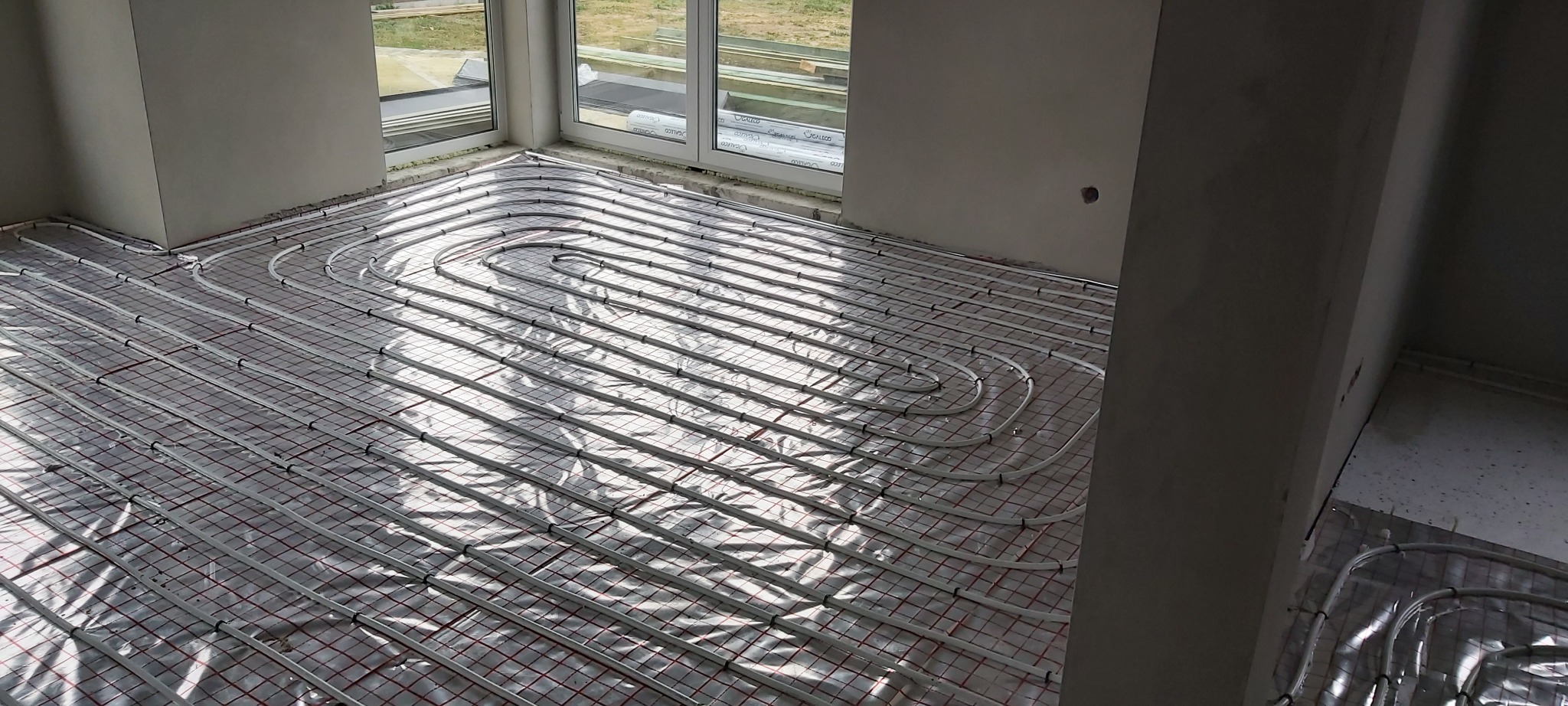 Montaż ogrzewania podłogowego w Starym Mieście: rury grzewcze ułożone na siatce, przygotowane do zalania wylewką.