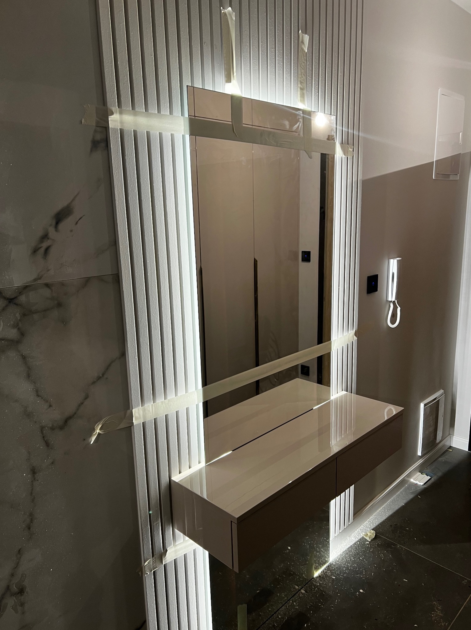 Nowoczesna toaletka z lustrem i lamelami dekoracyjnymi w trakcie montażu, zabezpieczona taśmą malarską.