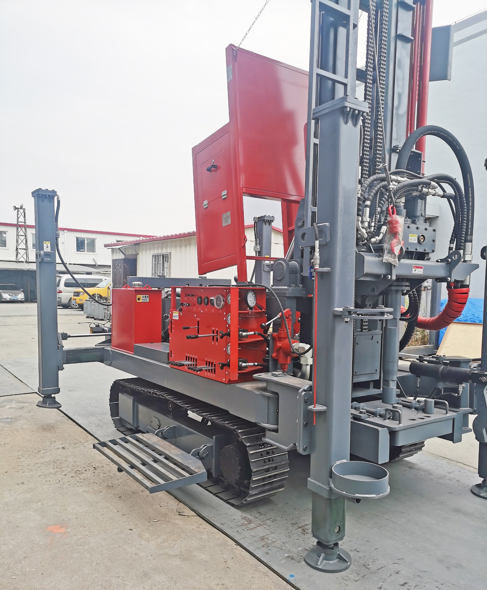 Mobilna wiertnica na gąsienicach z czerwonym panelem sterowania i wysuwanymi podporami hydraulicznymi, przygotowana do wiercenia.