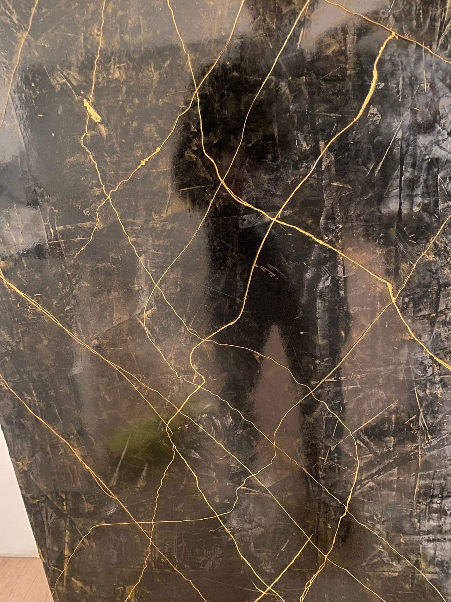 Czarna ściana z efektem marmuru i złotymi żyłkami, imitacja kintsugi.