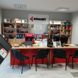 Biuro firmy dekarskiej Regamet z ekspozycją fragmentu dachu z blachy, biurkiem, krzesłami i półkami z próbkami produktów.