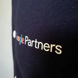 Granatowa koszulka z nadrukiem 'Google Partners', widoczna z bliska pod kątem, materiał lekko pognieciony.