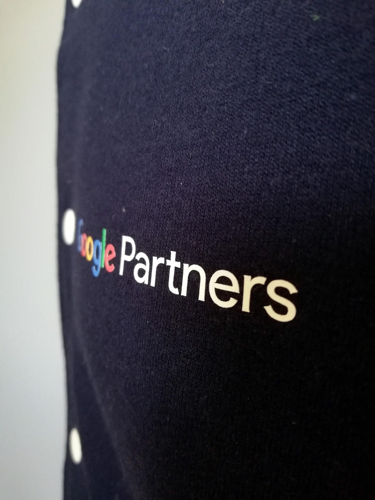 Granatowa koszulka z nadrukiem 'Google Partners', widoczna z bliska pod kątem, materiał lekko pognieciony.