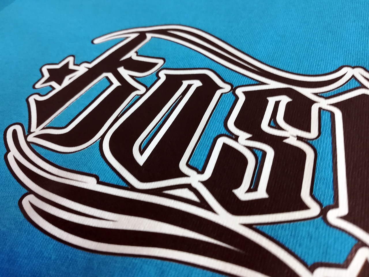 Zbliżenie na niebieską tkaninę z nadrukiem w stylu gotyckim, wykonanym techniką transferu solwent, widoczne detale tekstury materiału i precyzja wykonania nadruku.