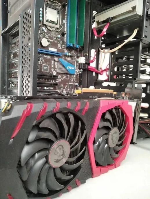 Wnętrze obudowy komputera stacjonarnego z widoczną kartą graficzną MSI z dwoma wentylatorami i czerwonymi akcentami, płytą główną z elementami chłodzenia oraz dyskiem twardym.