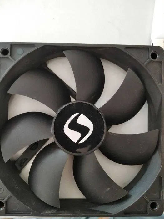 Czarny wentylator komputerowy z widocznym logo producenta na środku, leżący na białym tle.