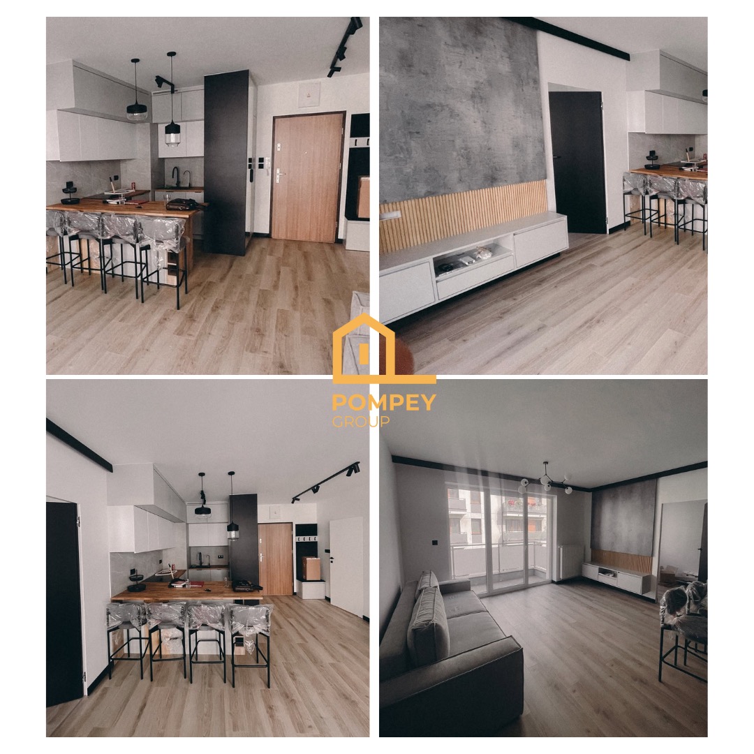 Nowoczesne wnętrze mieszkania po remoncie: jasna kuchnia z barkiem, salon z szarą sofą i ścianą dekoracyjną. Drewniana podłoga, minimalistyczne oświetlenie.