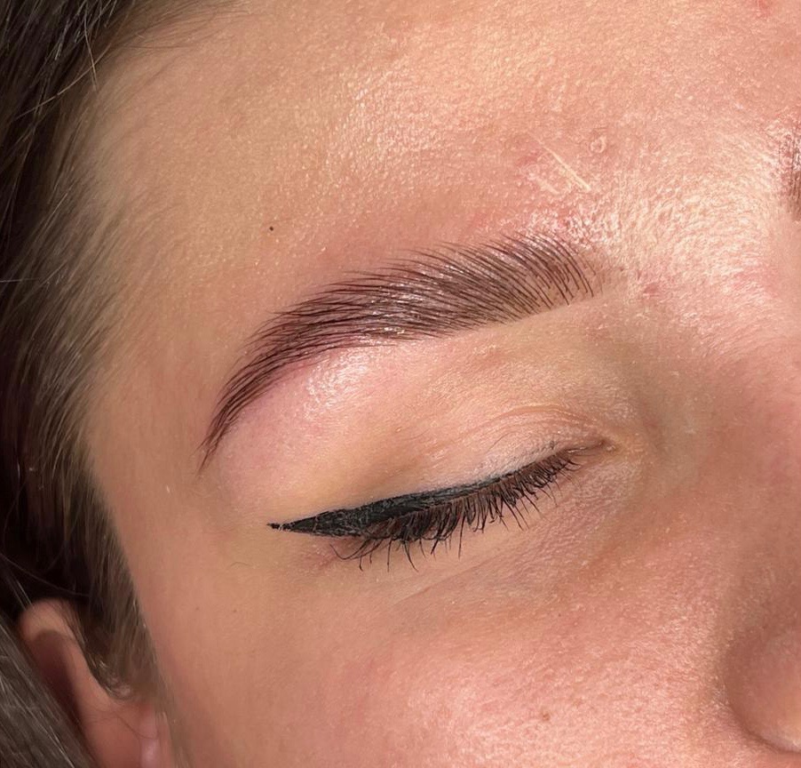 Detaliczny widok oka z precyzyjną czarną kreską i wystylizowanymi, błyszczącymi brwiami, podkreślającymi naturalny kształt.