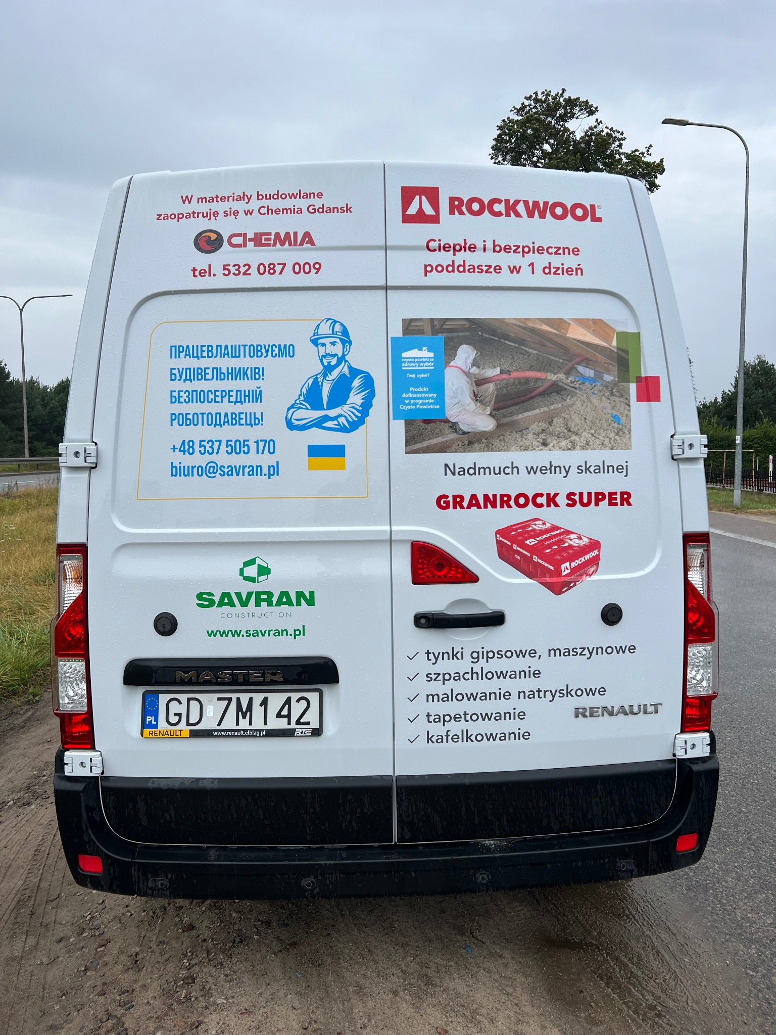 Tył białego samochodu dostawczego z reklamami firm budowlanych, w tym ocieplenia poddasza wełną skalną Rockwool Granrock Super, oraz listą usług: tynki gipsowe maszynowe, szpachlowanie, malowanie...