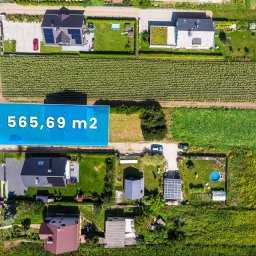 KATARZYNA MIGAS-SKIBA - Widok z lotu ptaka na działkę z zaznaczonym obszarem 565,69 m2, otoczoną domami, polami uprawnymi i drogą.