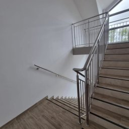 „Żelazny” Uslugi Spawalnicze - Wewnętrzne schody z drewnopodobnymi płytkami i metalową balustradą. Widok z góry, z naciskiem na detale wykończenia i minimalistyczny design.