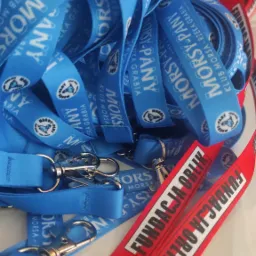 Stos niebieskich i czerwonych smyczy z nadrukowanymi logotypami i napisami, z metalowymi karabińczykami, ułożonych na białym tle.