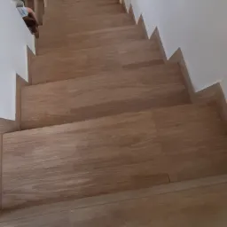 Schody wyłożone płytkami imitującymi drewno, widok z góry, jasne wnętrze.