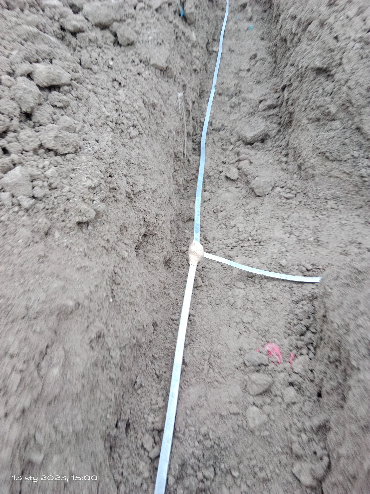 Wykop w ziemi z wytyczonym przebiegiem kabla w Opolu, widoczny przewód oznaczający trasę.