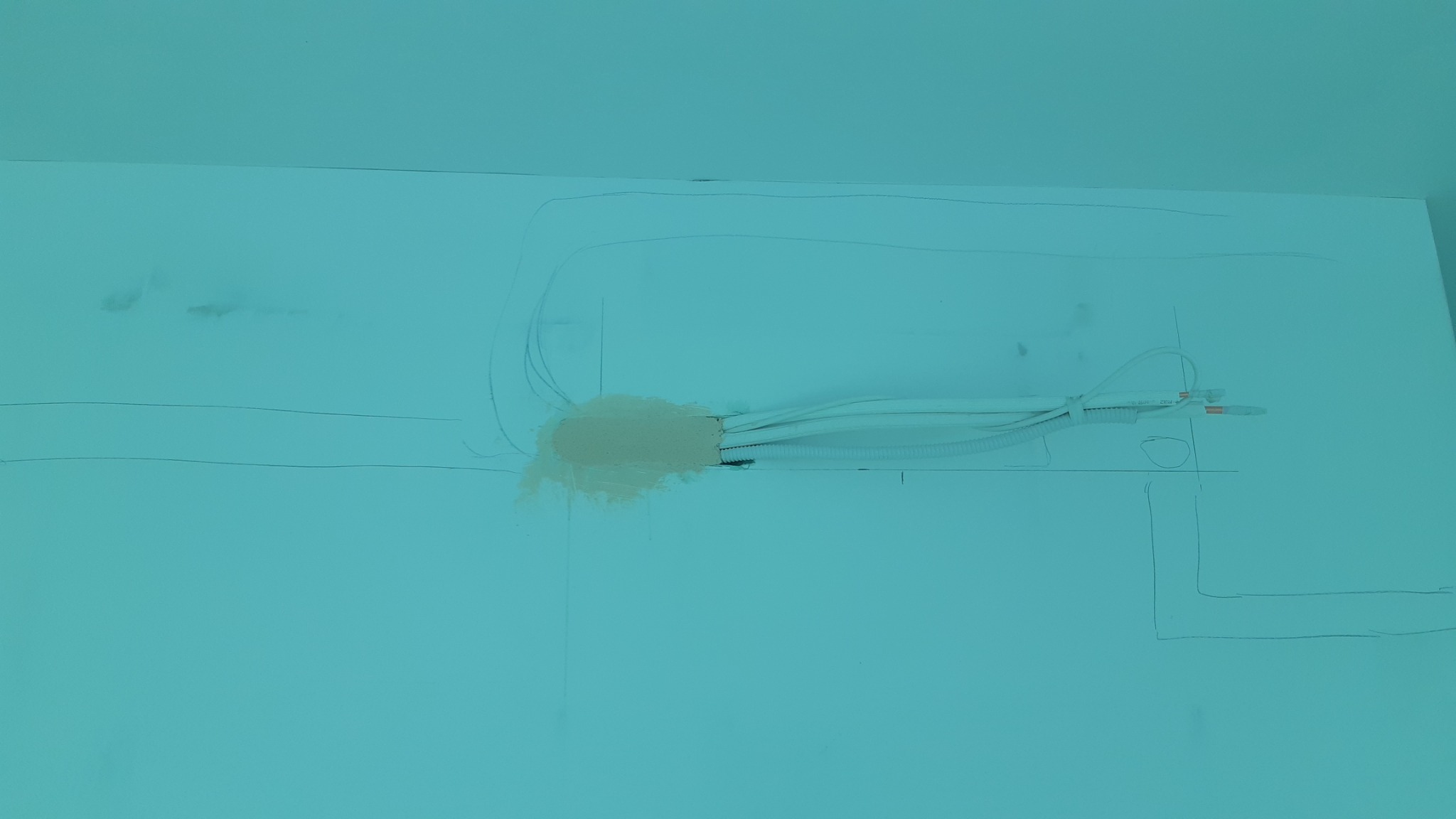 Ślady po instalacji przewodów w ścianie, zamaskowane gipsem, z widocznymi liniami pomocniczymi narysowanymi ołówkiem.