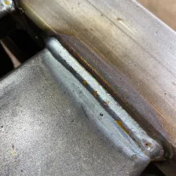 Spoina łącząca dwa metalowe profile, widoczne ślady ciepła i niewielkie odpryski po procesie.