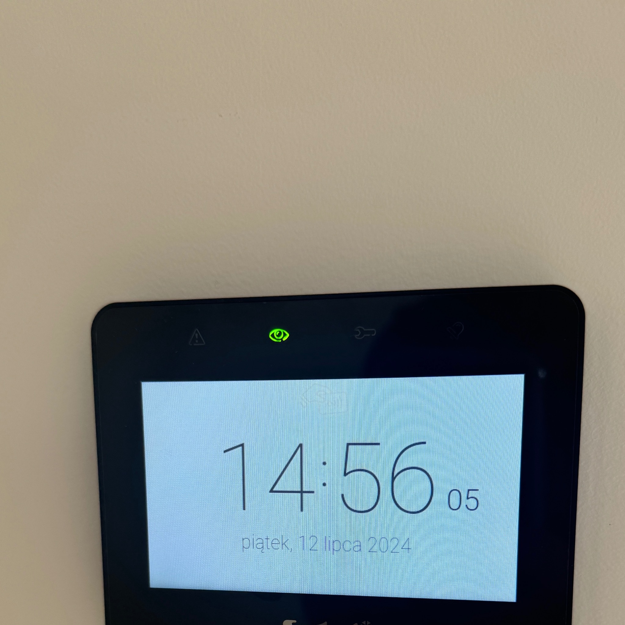 Ekran dotykowy z widocznym czasem 14:56:05 i datą piątek, 12 lipca 2024, prawdopodobnie element systemu alarmowego lub monitoringu.