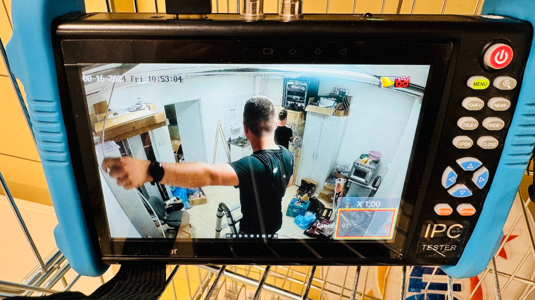 Ekran testera kamer IP z widokiem z kamery monitoringu w pomieszczeniu z wyposażeniem kuchennym i narzędziami, data i godzina na ekranie