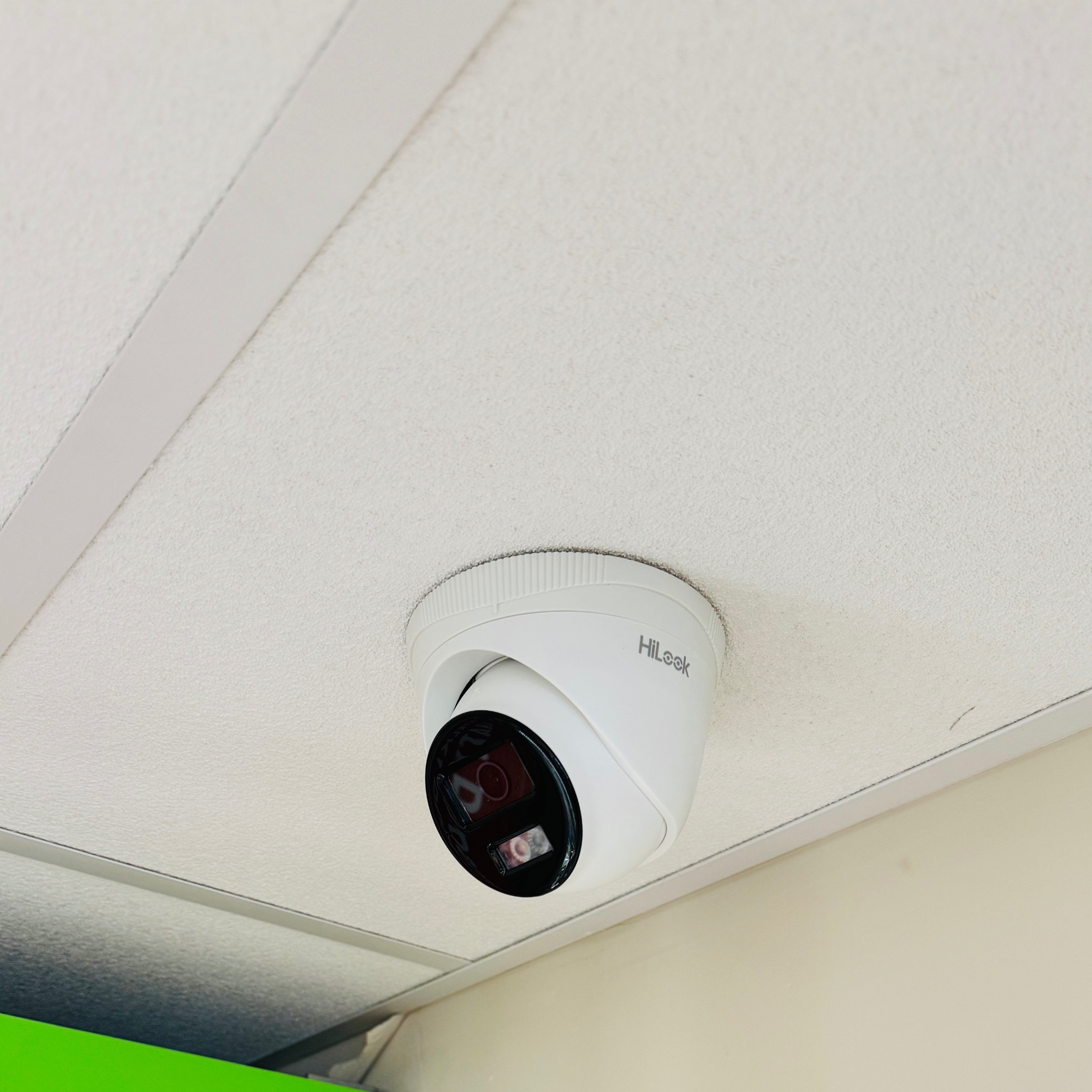 Kopułkowa kamera HiLook zamontowana na białym suficie podwieszanym z widocznymi elementami konstrukcyjnymi.