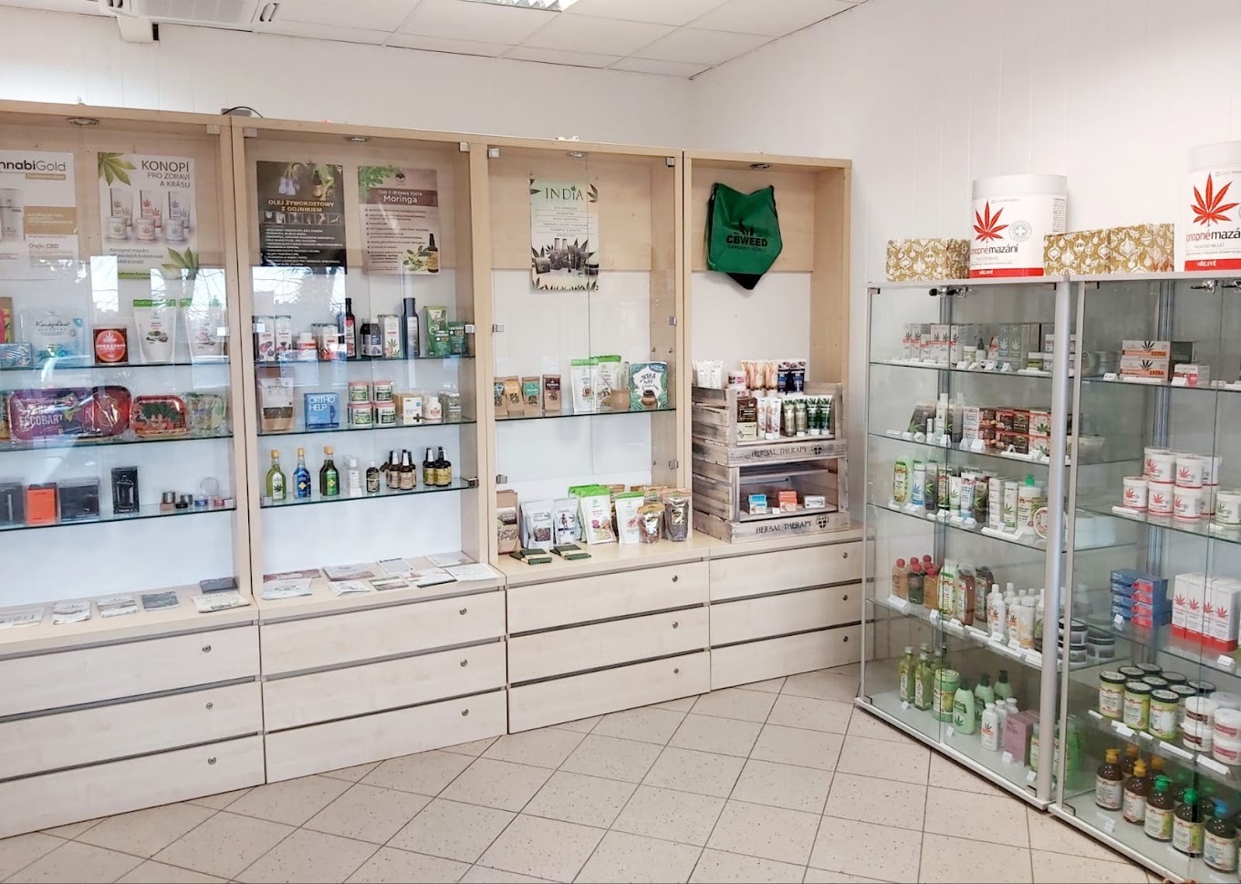 Wnętrze sklepu z produktami konopnymi: witryny z olejkami CBD, kosmetykami konopnymi i suplementami diety, torba z logo CBWEED, półki z kremami i maściami konopnymi.