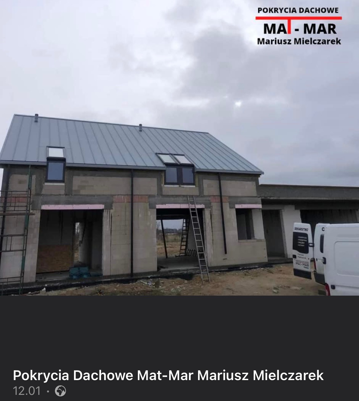 Surowy budynek w trakcie budowy z szarym metalowym pokryciem dachowym, widoczne okna dachowe, drabiny i częściowo ocieplone otwory okienne, logo firmy dekarskiej w górnej części zdjęcia.
