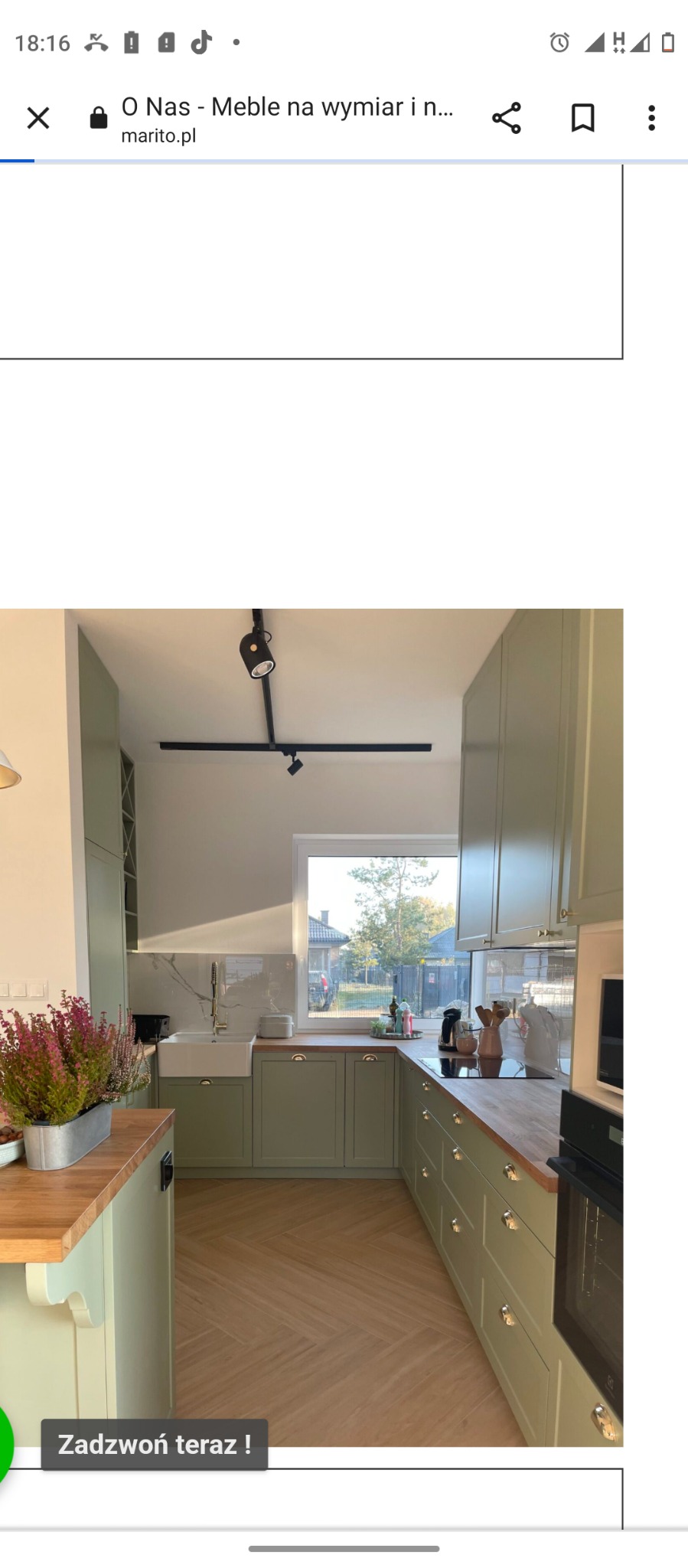 Jasna kuchnia w odcieniach zieleni z drewnianym blatem, widok na zewnątrz przez okno, podłoga ułożona w jodełkę, na blacie kuchennym ustawione akcesoria i zioła w doniczce.