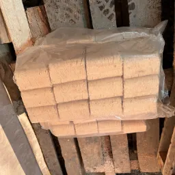 Pakiet brykietu drzewnego w przezroczystej folii, ułożony na drewnianej palecie w magazynie.