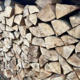 Rząd ułożonych, pociętych kawałków drewna na opał, widoczne słoje i kora, ułożone na palecie na zewnątrz.