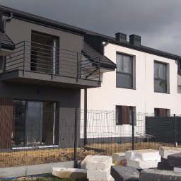 TermoHouse usługi remontowo budowlane Patryk Goleń - Nowo wybudowane domy w trakcie wykańczania elewacji, widoczne rusztowania i materiały budowlane, jeden z pracowników na drabinie na balkonie.