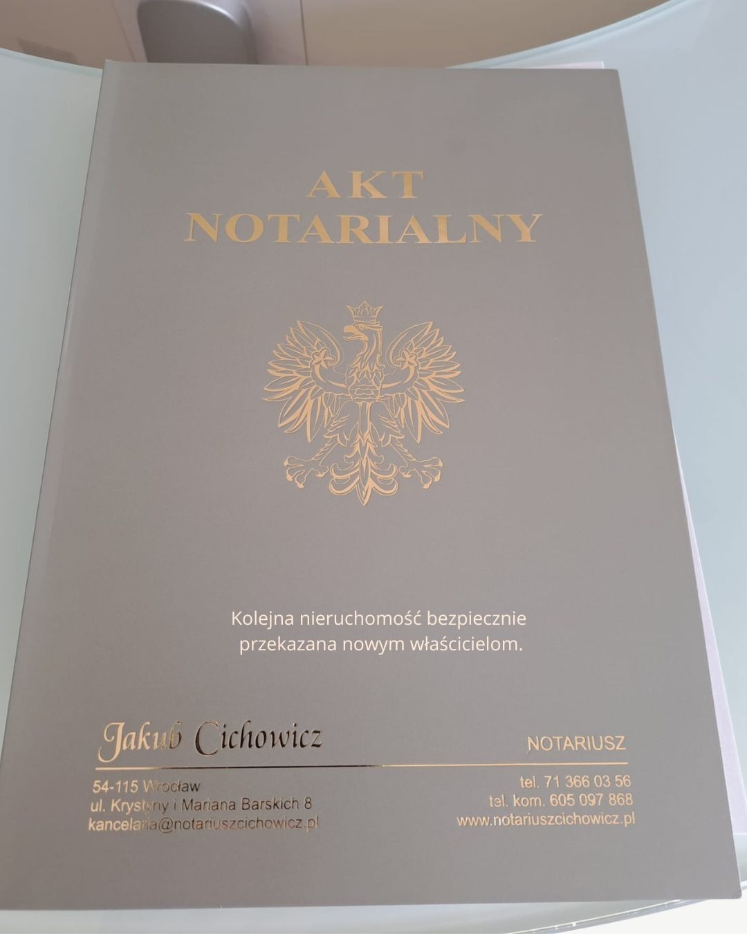 Szary akt notarialny z godłem i napisem 'Kolejna nieruchomość bezpiecznie przekazana nowym właścicielom', sygnowany przez notariusza Jakuba Cichowicza z Wrocławia.