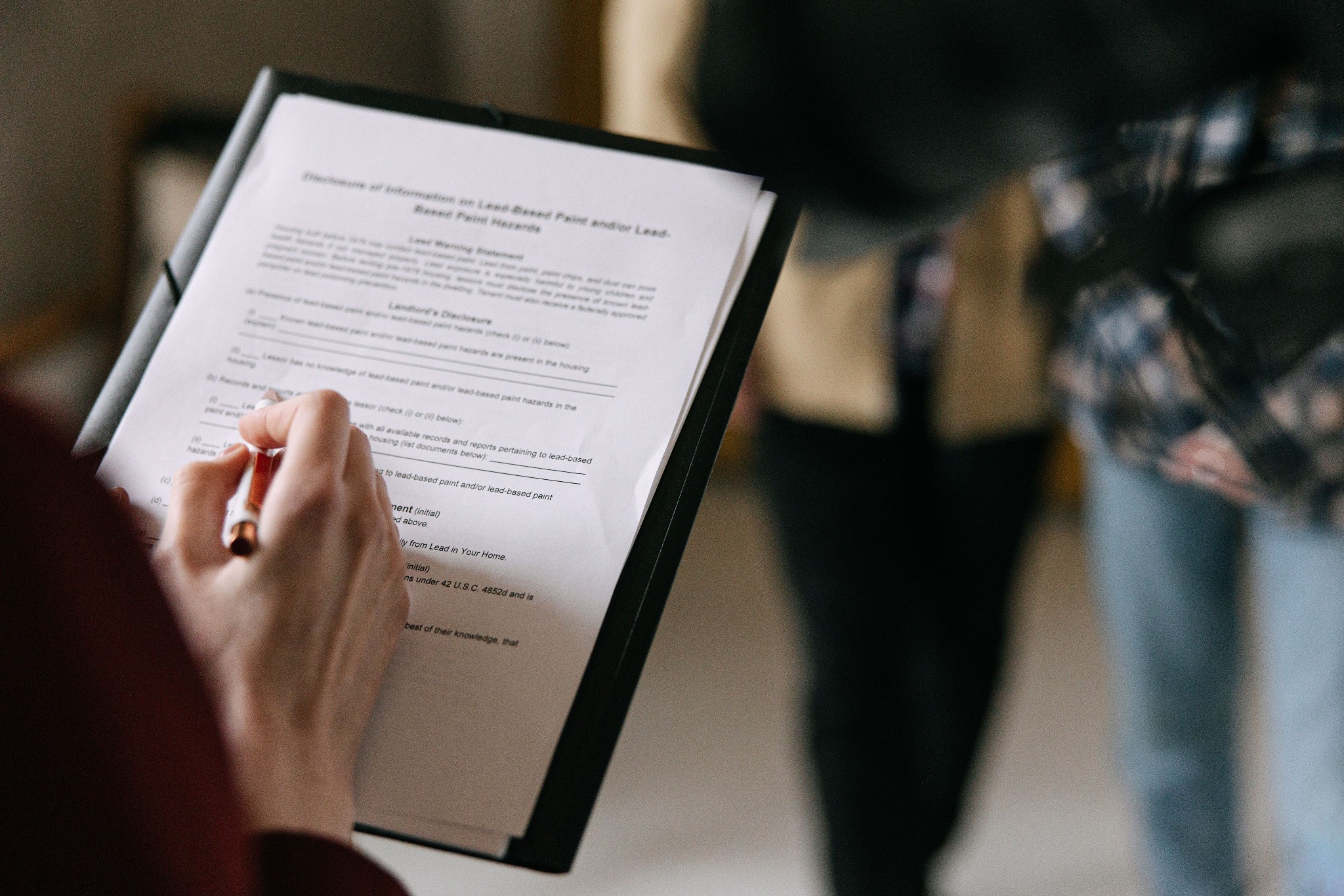 Wypełnianie formularza o zagrożeniach związanych z farbami na bazie ołowiu. Osoba podpisuje dokument w obecności agenta nieruchomości.