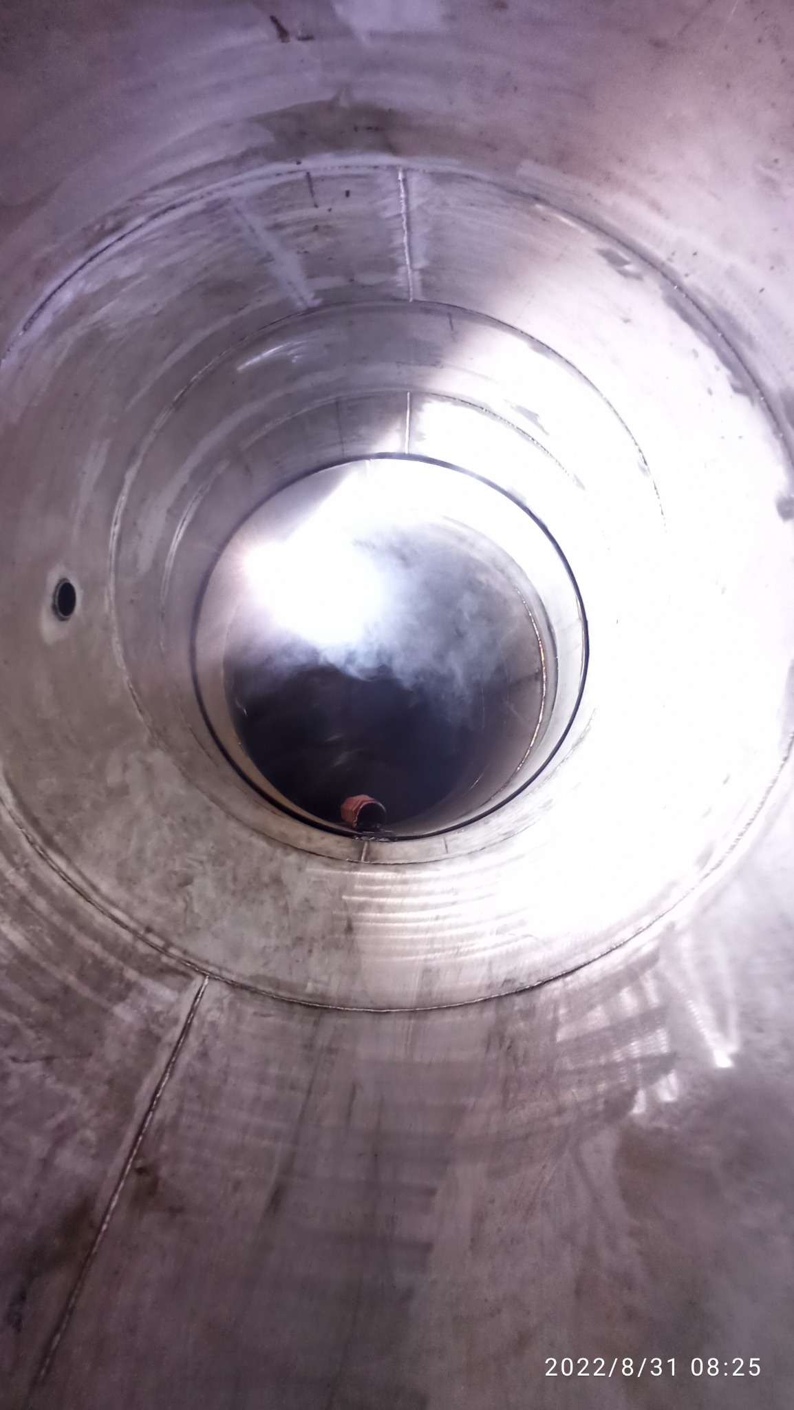 Wnętrze stalowej rury z widocznymi spawami i dymem w oddali