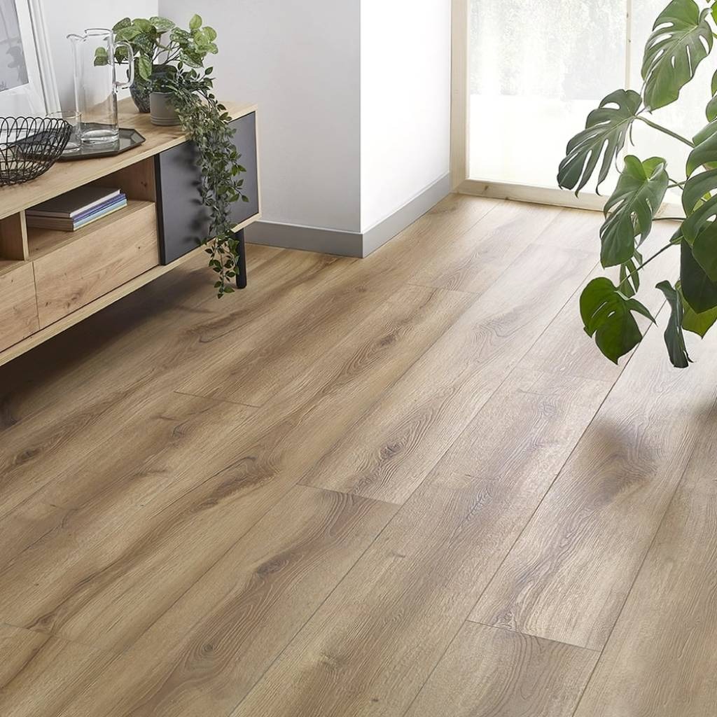 Jasne panele podłogowe ułożone w salonie z drewnianą komodą i zielonymi roślinami, widok z niskiej perspektywy.