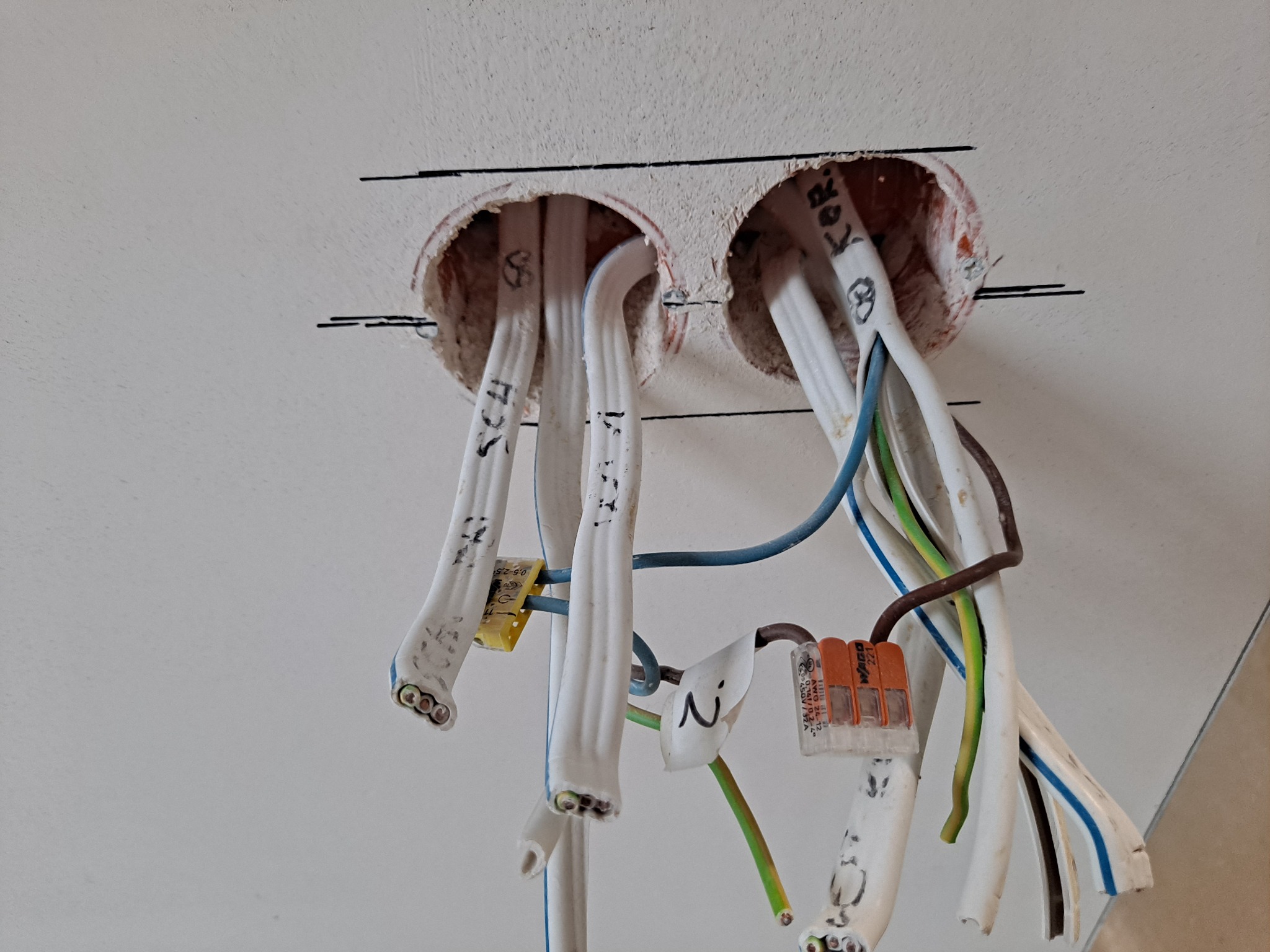 Przygotowane otwory w suficie z wystającymi przewodami elektrycznymi i złączkami WAGO, widoczne oznaczenia na kablach, instalacja w trakcie realizacji w Bielsku-Białej.