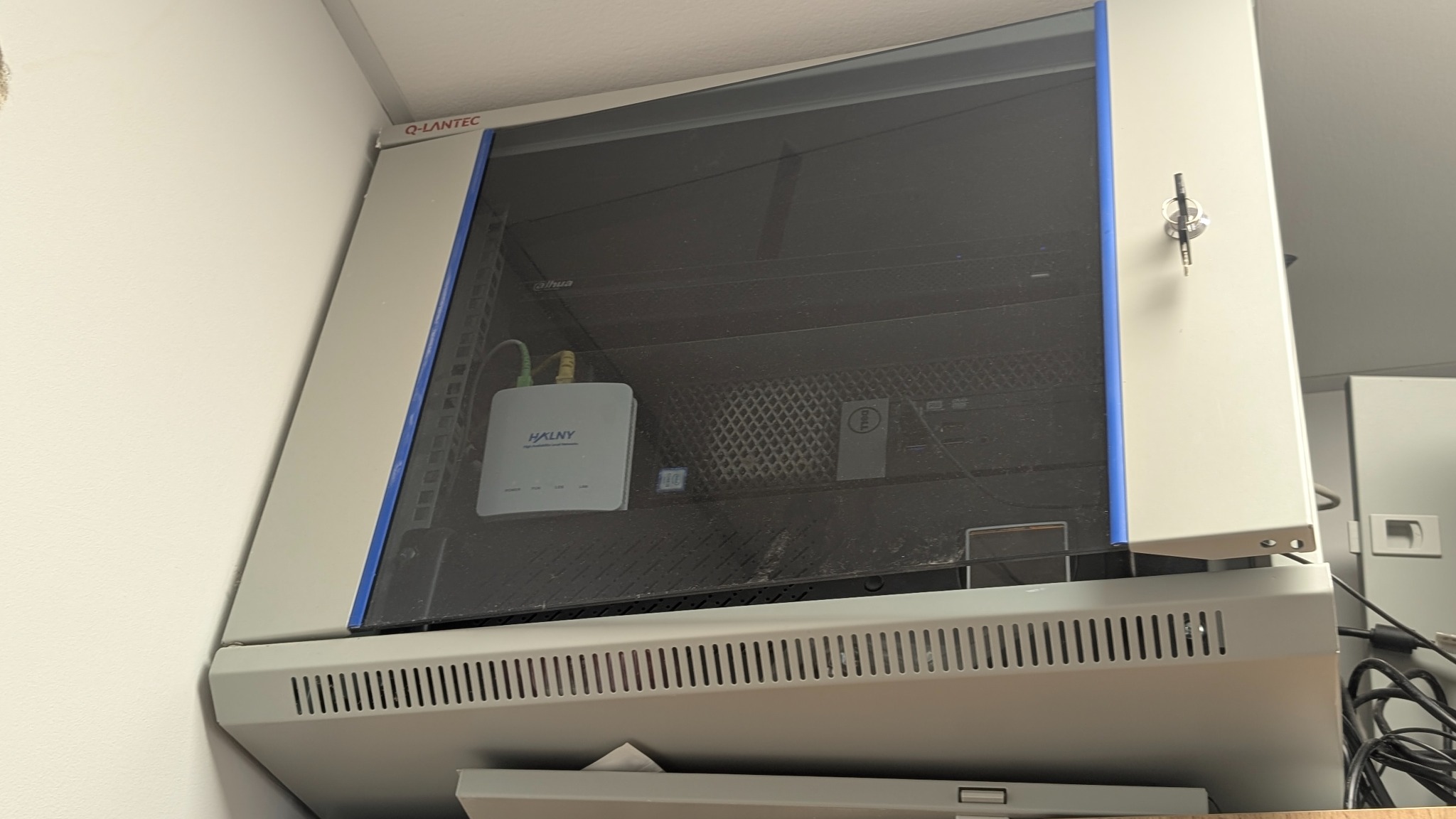 Szafa rack Q-Lantec z routerem HALNY i serwerem Dell, zabezpieczona zamkiem. Widoczne okablowanie i elementy sieciowe.