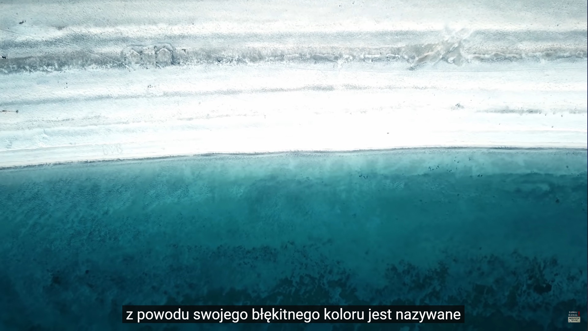 Panoramiczny widok z lotu ptaka na jezioro o turkusowej wodzie i białe, piaszczyste brzegi.