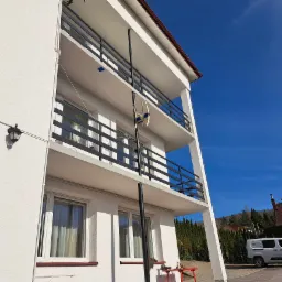 Elewacja budynku z balkonami zabezpieczonymi czarnymi barierkami w Porażu, na jednym z balkonów widoczna antena satelitarna.